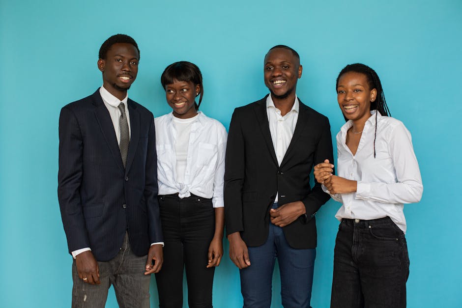A group of smiling young professionals in a studio setting against a blue backdrop.